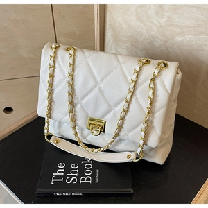 Detail of white quilted leather bag with gold chain strap and metal turn-lock closure