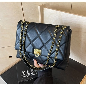 Close-up of black quilted chain bag with gold rotary lock and pebbled leather texture