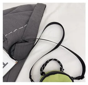 Detail showing the adjustable black shoulder strap on a green nylon mini bag