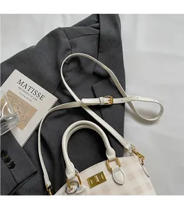 Detail view of checkered handbag with gold metal clasp and adjustable shoulder strap