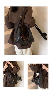 Detail of black leather hobo bag with a cute brown dachshund pendant and gold hardware