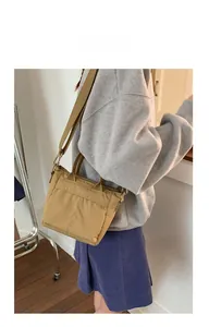 Detail view of khaki canvas crossbody tote bag with side metal buckles and carry strap