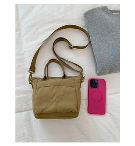 Detail view of the khaki canvas tote bag showing the texture, handle, and long shoulder strap