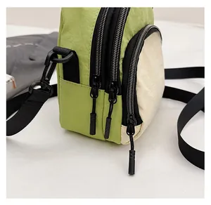 Detail view of smooth three-layer zippers and textured nylon fabric on the crossbody bag