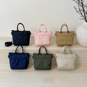 Detailed view of various colorful mini tote bags displayed on a minimalist stone staircase
