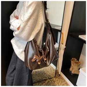 Deep brown glossy leather bucket bag with an adjustable strap and a cute dachshund pendant