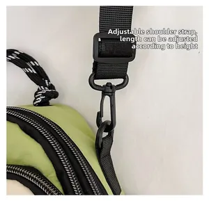 Detail of adjustable black nylon strap with plastic buckle on a green crossbody bag