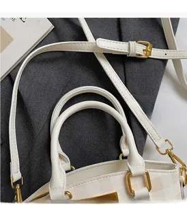 Detail of minimalist cream checkered handbag showing double handles and gold metal hardware