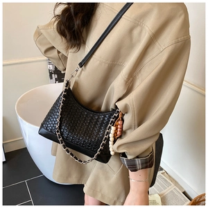 Detail of black woven shoulder bag with silver chain and wooden bead charm accessory