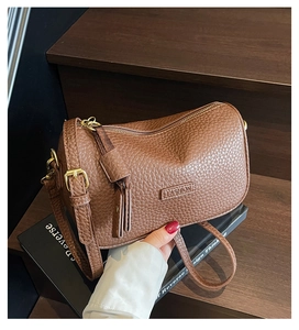 Détail du sac marron foncé en cuir litchi avec ferrures dorées et logo FASHION