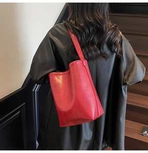 Vue arrière d'un mannequin portant un grand sac cabas rouge sur un escalier en bois
