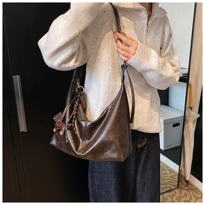 Detail of dark brown leather hobo bag with a dog charm and wide shoulder strap