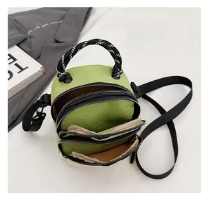 Detailed view of green shell bag featuring three layers of zippers and woven handles