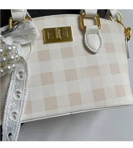 Detail of checkered woven texture with gold square buckle and elegant pearl charm decor