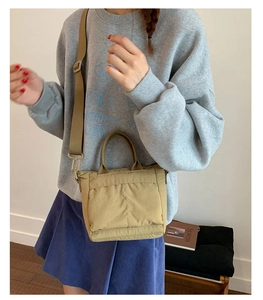 Detail of khaki nylon crossbody tote bag with adjustable strap shown on model