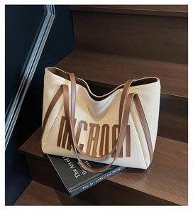 Détail du sac cabas en toile avec lettres NCROI en cuir marron sur escalier boisé