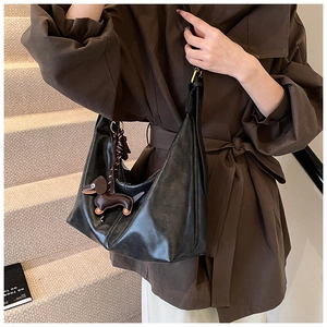 Close-up of black PU leather hobo bag with a brown dachshund charm and gold hardware detail