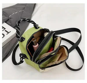 Detail of green nylon crossbody bag showing triple zipper layers and large capacity