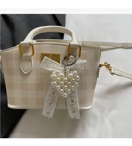 Detail of checkered handbag with heart pearl bow charm and golden metal hardware
