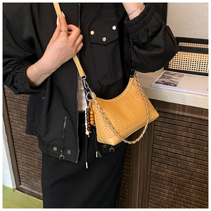 Detail of yellow woven leather armpit bag with silver chain and beaded charm