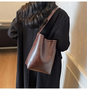 Vue arrière du mannequin portant un grand sac cabas marron avec un manteau noir