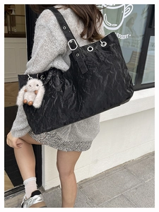 Gros plan du sac cabas plissé noir avec œillets argentés et breloque lapin blanc