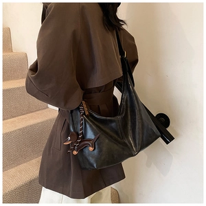 Detail of a large black leather hobo bag with a brown dachshund charm and golden hardware