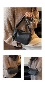 Détail du sac Boston en cuir grainé noir avec bandoulière rayée et plaque en métal de mode