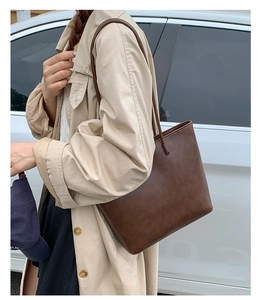 Detail view of large dark brown leather tote bag showing fine texture and shoulder straps