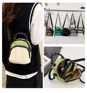 Detail of multi-compartment nylon shell bag with zip pockets and woven top handle