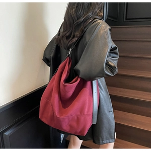 Modèle portant un grand sac cabas bordeaux en toile avec bandoulière en cuir noir