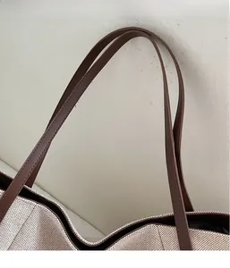 Gros plan des poignées en cuir marron et de la texture tissée d'un grand cabas