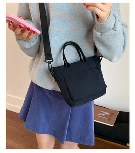 Detail of black canvas tote bag with front pocket and detachable woven shoulder strap