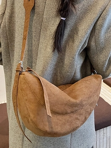 Braune Halbmond-Tasche aus Wildlederimitat getragen mit einem grauen Wollsakko für Damen