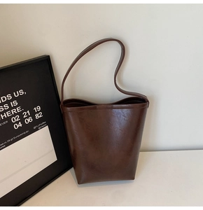Détail du sac seau marron foncé avec texture cuir huilé vintage et large bandoulière