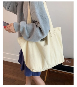 Vue latérale du grand sac cabas en toile crème porté par un mannequin pour le quotidien