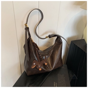 Detail of dark brown leather crescent bag with dachshund charm and gold buckle