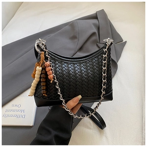 Detail of a black woven leather hobo bag with a silver chain and vintage beaded charm