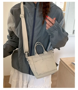 Detailed shot of beige nylon mini tote bag with adjustable strap and layered pocket