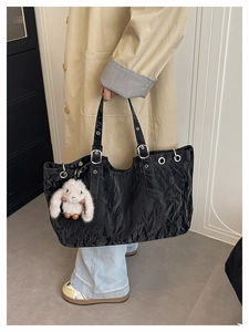 Détail du sac cabas plissé noir avec œillets métalliques et breloque lapin en peluche