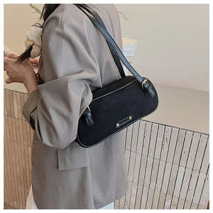 Detalle del bolso baguette minimalista en ante negro con textura y correa ajustable en modelo