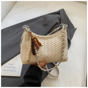 Detail of cream woven hobo bag with silver chain strap and beaded pendant detail
