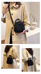 Detail of a black nylon shell bag featuring dual straps and a minimalist crossbody design
