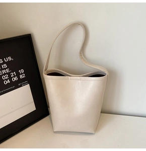 Détail du sac seau blanc crème montrant la texture du similicuir et la bandoulière fine