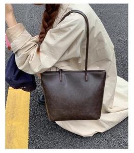 Deep brown tote bag detail with vintage leather texture and slim shoulder straps