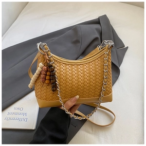 Detail of yellow woven leather shoulder bag with wooden beads and silver chain handle