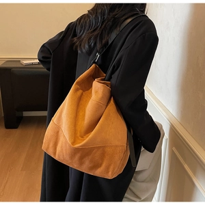 Détail du grand sac seau en daim marron avec large bandoulière en cuir noir chic