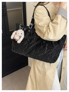 Détail d'un sac cabas noir brillant avec texture froissée et anneau en métal argenté
