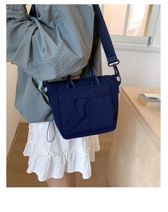 Detail of dark blue nylon handbag with adjustable strap shown on model in a casual setting
