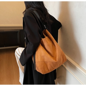 Mannequin portant un grand sac cabas mat caramel dans un cadre intérieur épuré